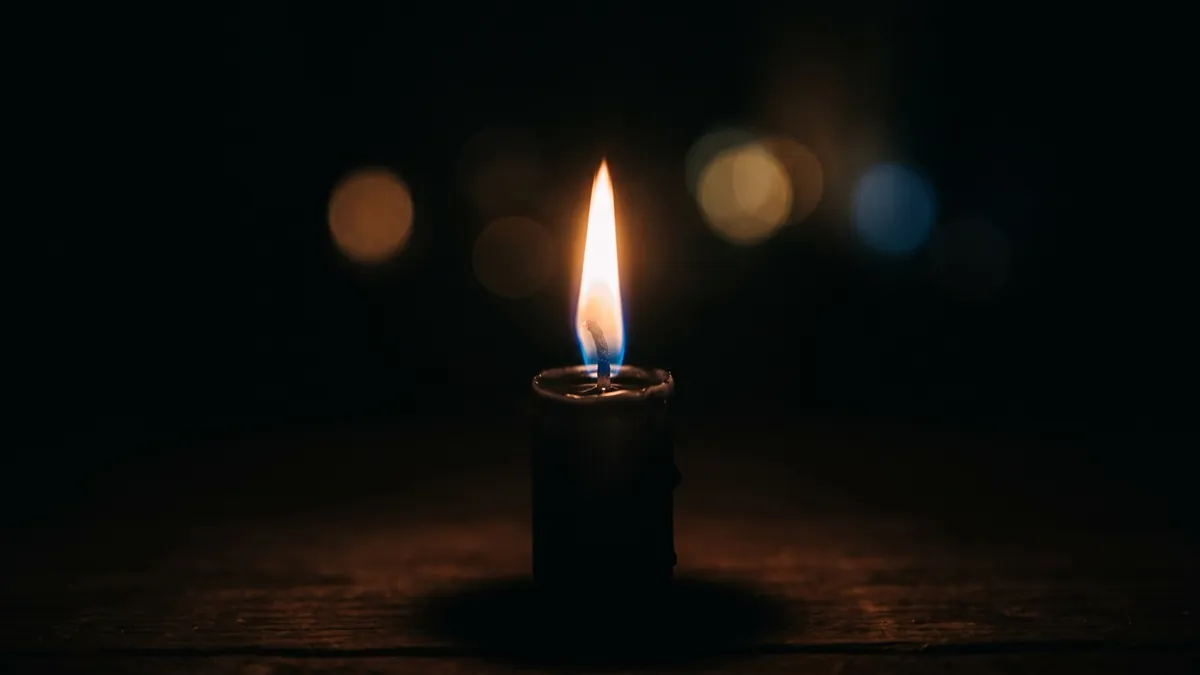 A single candle flame burning in the dark